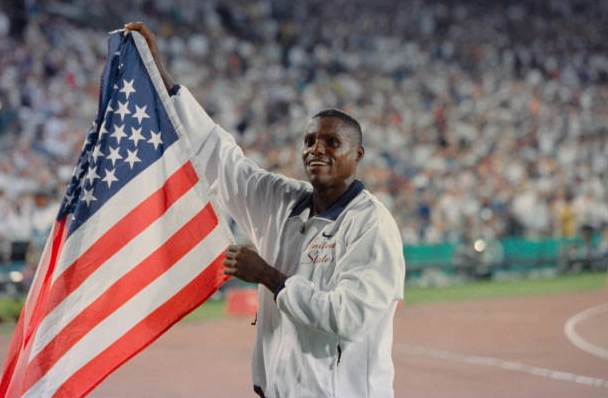 Carl Lewis rạng rỡ vẫy cao lá cờ nước Mỹ ăn mừng chức vô địch môn nhảy xa tại Olympic mùa hè 1996 ở Atlanta